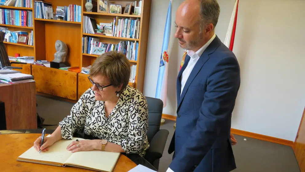 La secretaria de Estado, &Aacute;ngeles Heras, escribiendo en en el libro de firmas de Zona Franca ante el delegado David Regades.