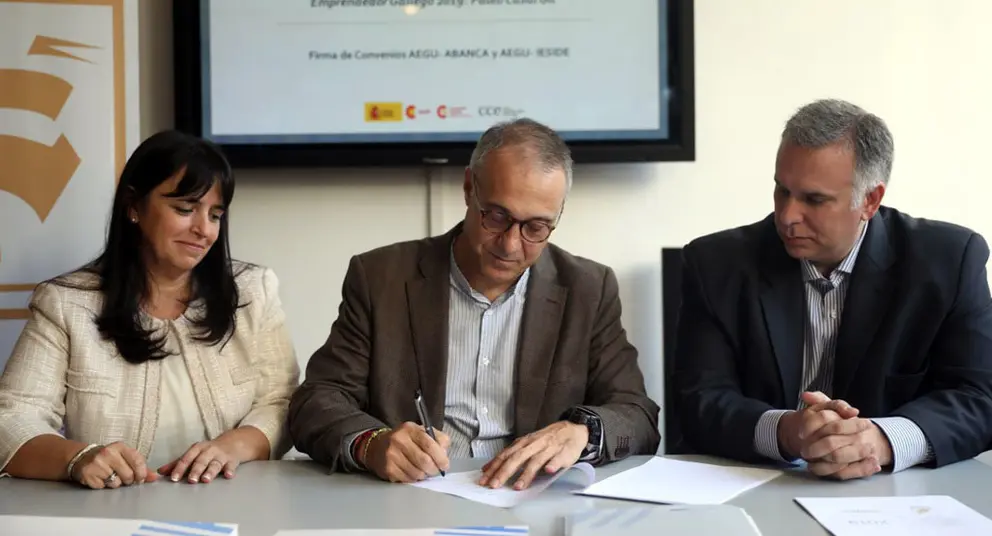Los representantes de AEGU con el director de No residentes de Abanca, , en la firma del convenio.