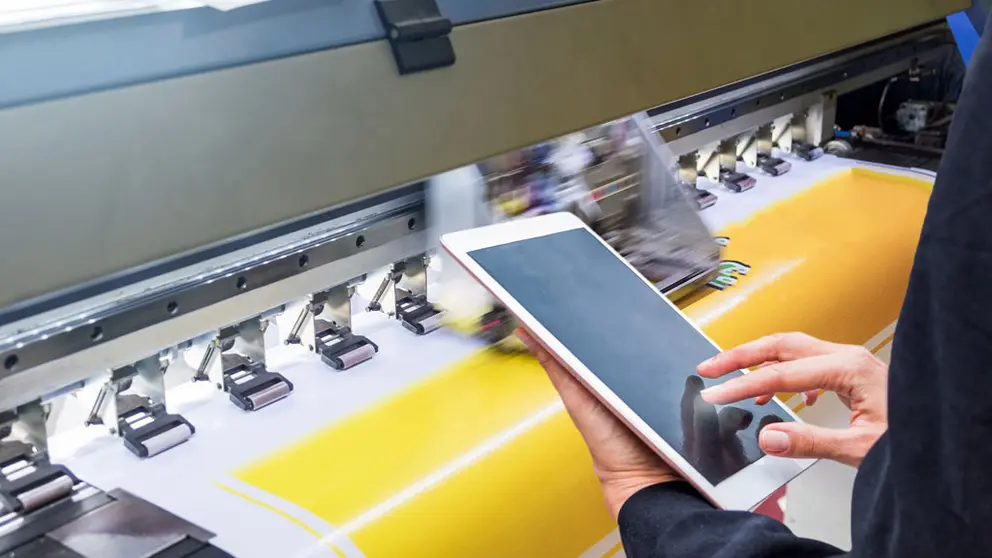 Technician touch control tablet on format inkjet printer during yellow vinyl paper